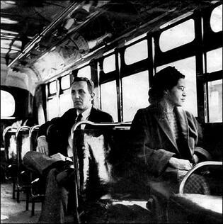 Rosa Parks on a Montgomery bus on December 21, 1956, the day Montgomery's public transportation system was legally integrated. Behind Parks is Nicholas C. Chriss, a UPI reporter covering the event. By https://www.loc.gov/rr/print/list/083_afr.html#ParksR, Fair use, https://en.wikipedia.org/w/index.php?curid=3034067