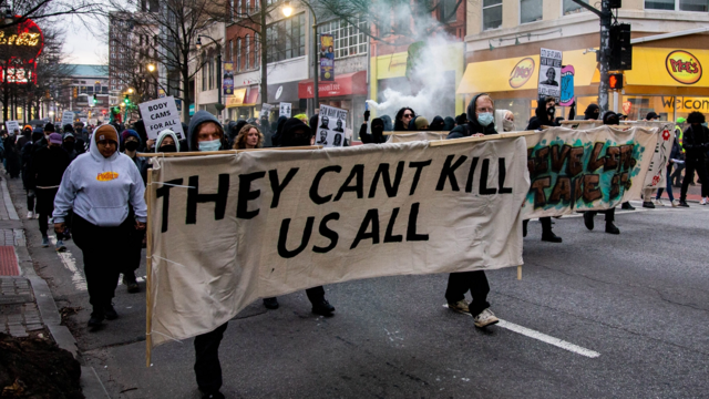 Stop Cop City protesters march in Atlanta behind banner reading, "They Can't Kill Us All."