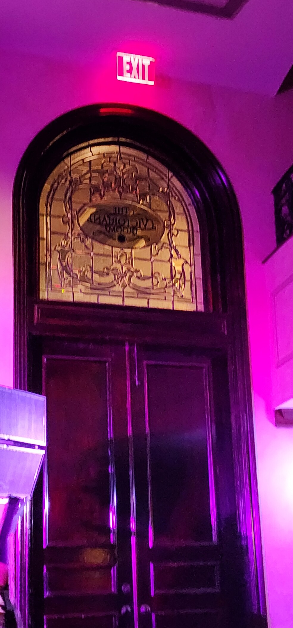 The ornate clear glass window at the top of the wooden door which is labeled The Victorian Room. 