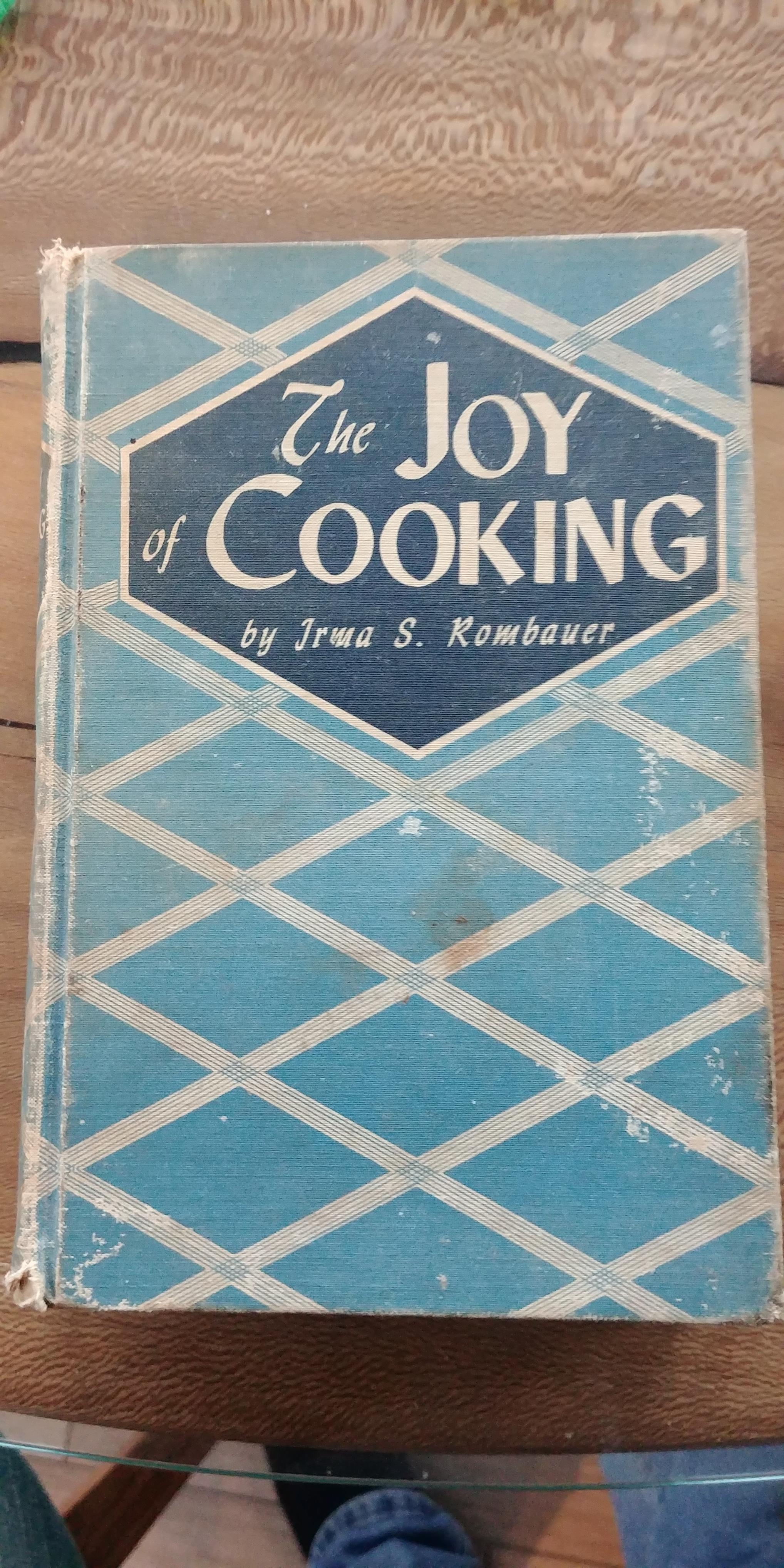 Cover of"The Joy of Cooking". It's a light blue with white lines making a diamond pattern. Author is is Irma Rombauer. 