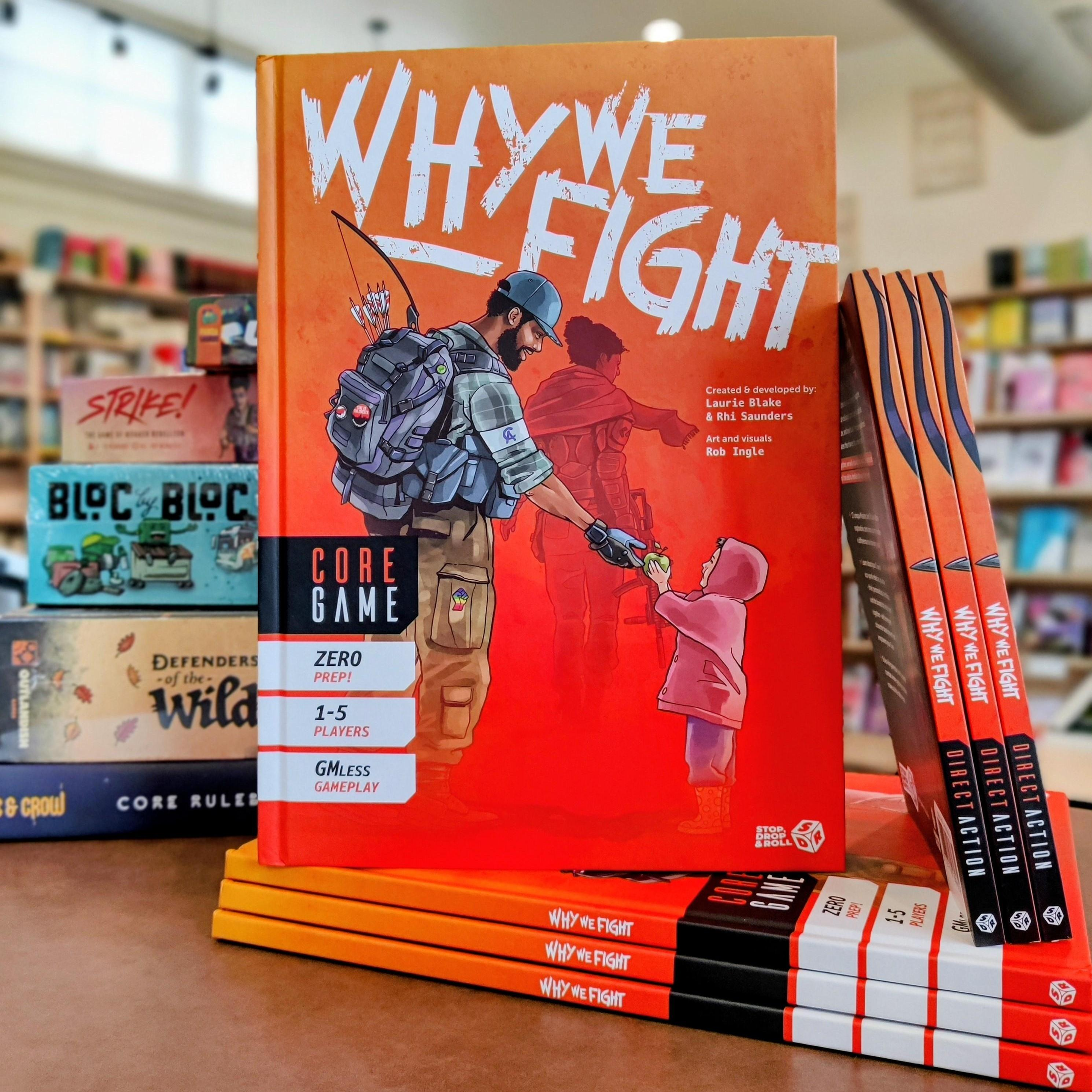 A photo of the "Why We Fight" core game book displayed at Firestorm Books. The orange cover features an illustration of a member of the Community Alliance handing a small child an apple. The character carries a bow and wears a backpack decorated with activist buttons.