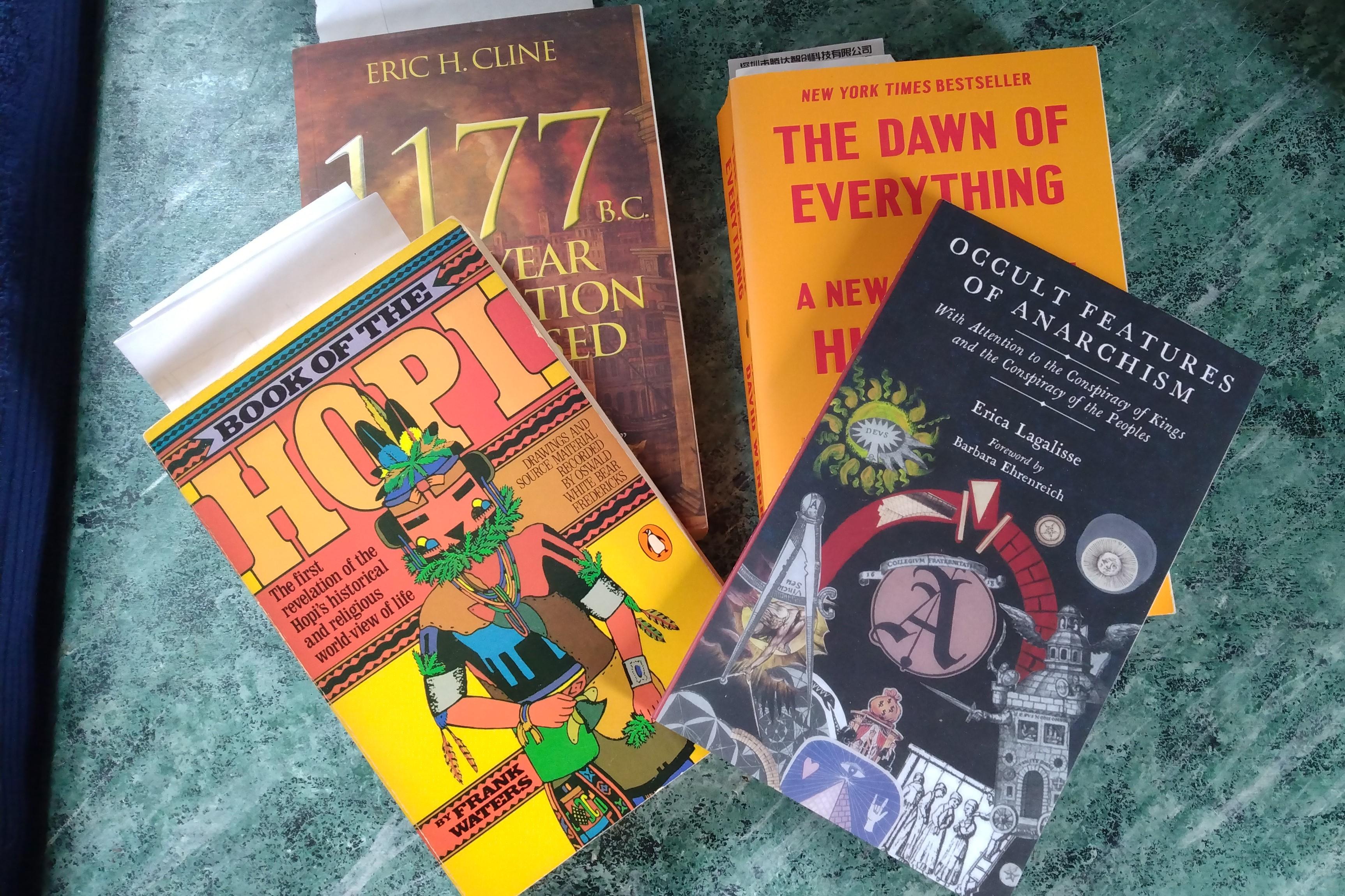 Four books on a table:
The Book of the Hopi by Frank Waters.
1177 BC - The Year Civilization Collapsed by Eric Cline.
The Dawn of Everything - A New History of Humanity by David Graeber and David Wengrow
The Occult Features of Anarchism - With Attention to the Conspiracy of Kings and the Conspiracy of the Peoples by Eric Lagalisse.
