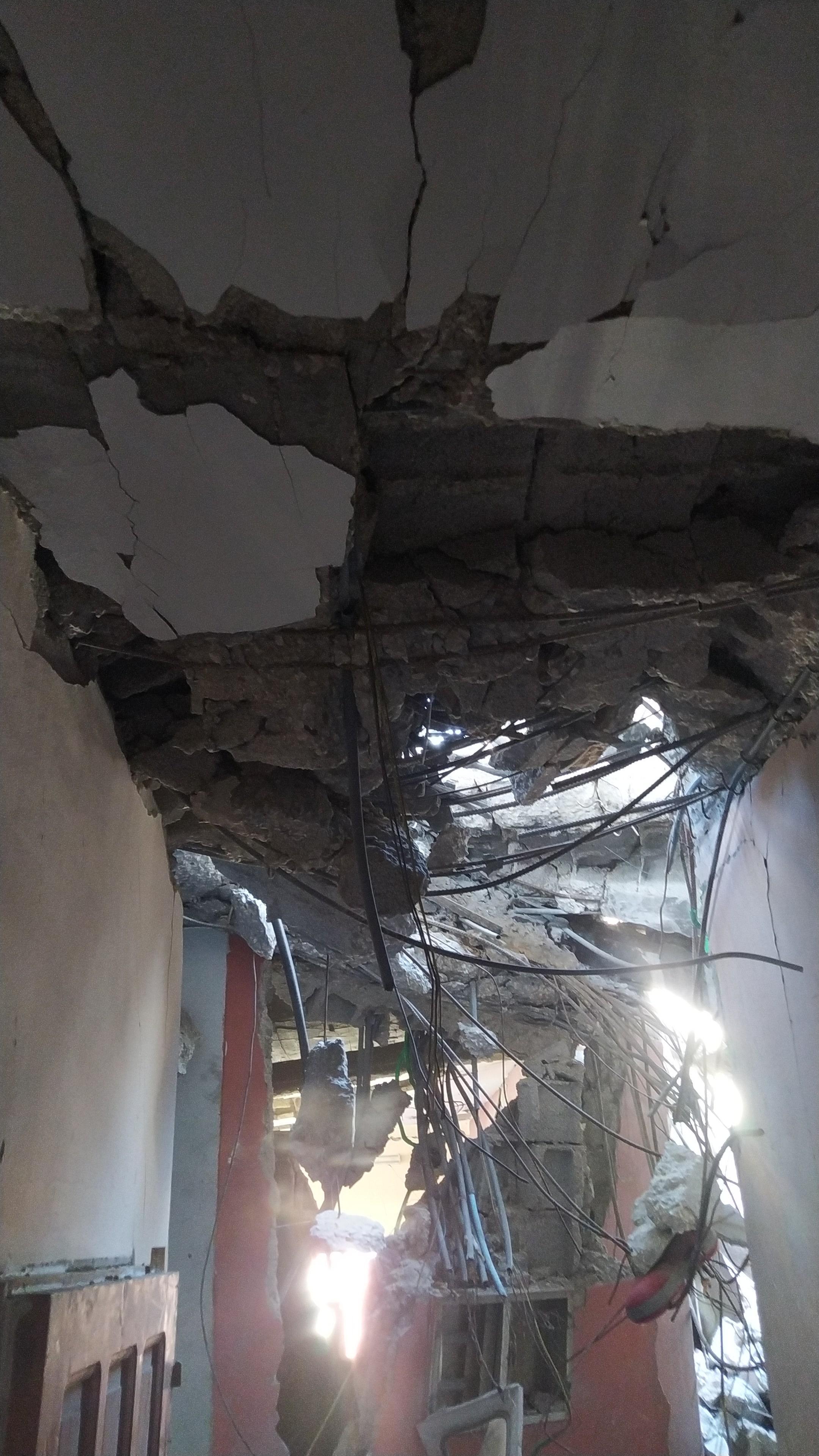 Inside a destroyed building. Sunlight streams in through a crack in the ceiling.