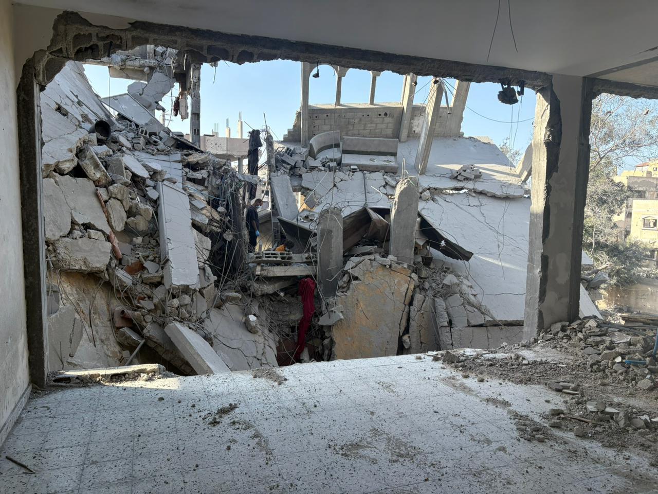 The interior of a destroyed house. The walls have completely disappeared, revealing the next house that also is completely destroyed.