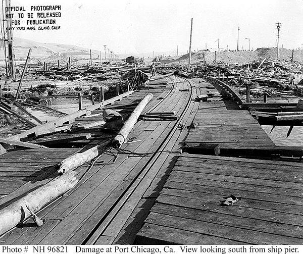 Damage at the Port Chicago Pier after the explosion of July 17, 1944. Naval Magazine, Port Chicago, California, damage resulting from the Port Chicago ammunition explosion disaster of July 17, 1944. From the source: "This view looks south from the Ship Pier, showing the wreckage of Building A-7 (Joiner Shop) at the right. There is a piece of twisted steel plating just to left of the long pole in left center." By Mare Island Navy Yard - http://www.history.navy.mil/photos/images/h96000/h96821.jpg U.S. Naval Historical Center, Public Domain, https://commons.wikimedia.org/w/index.php?curid=1992404
