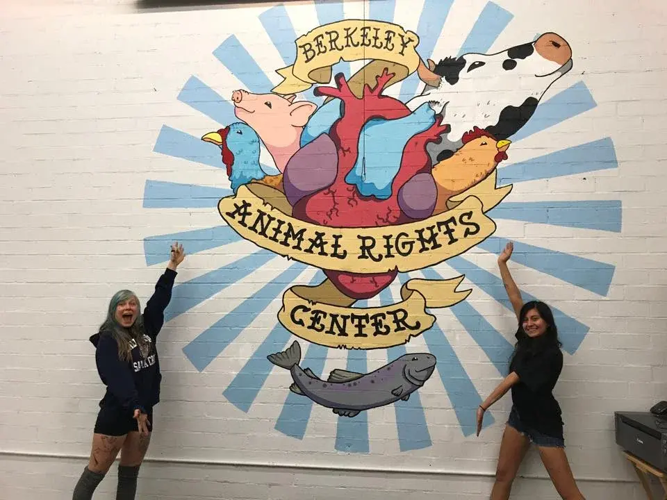 Berkeley Animal Rights Center mural with animals and a heart, two people posing.