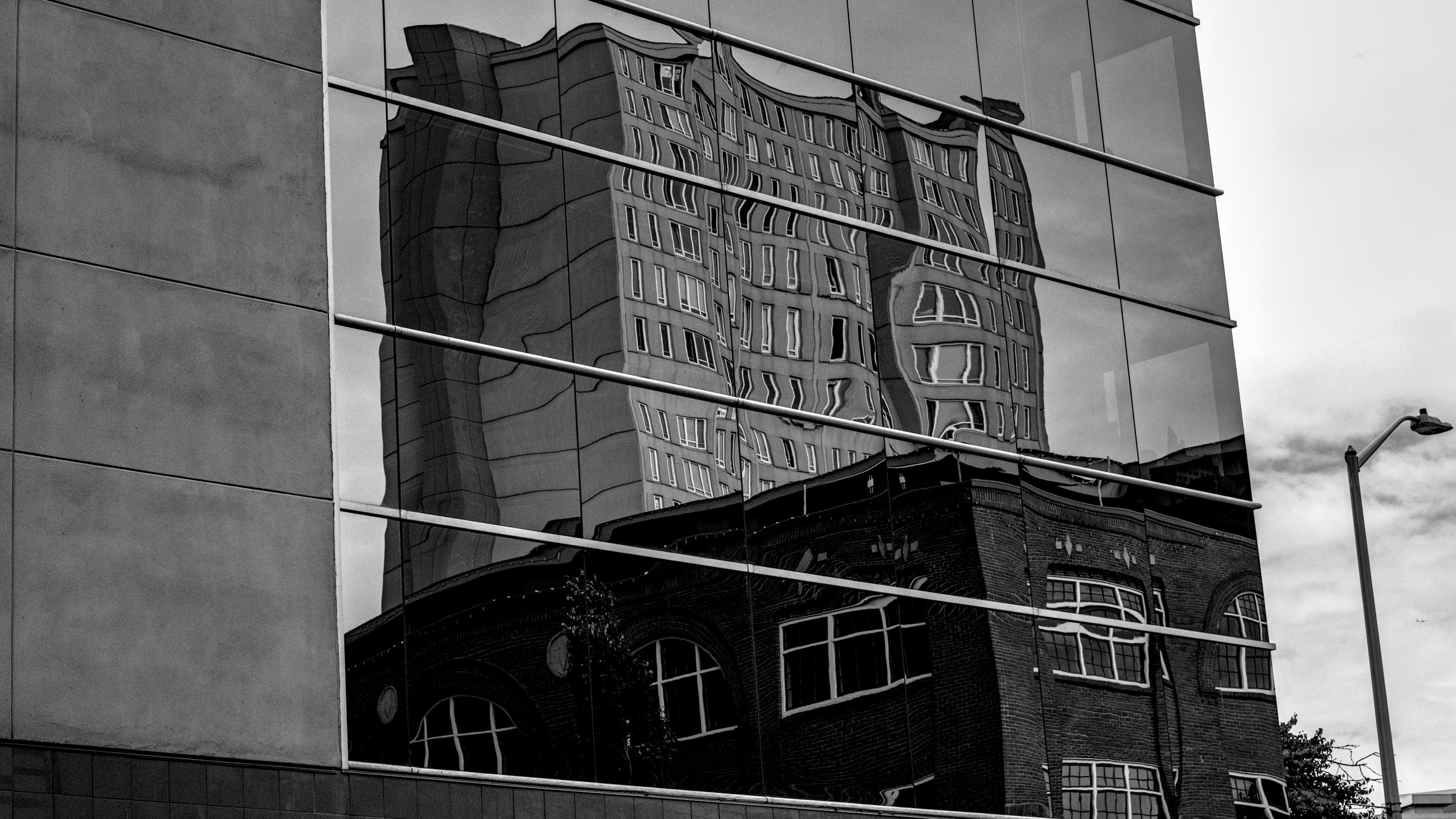Monochrome photo of windows of a building downtown, where another building is being reflected in the windows