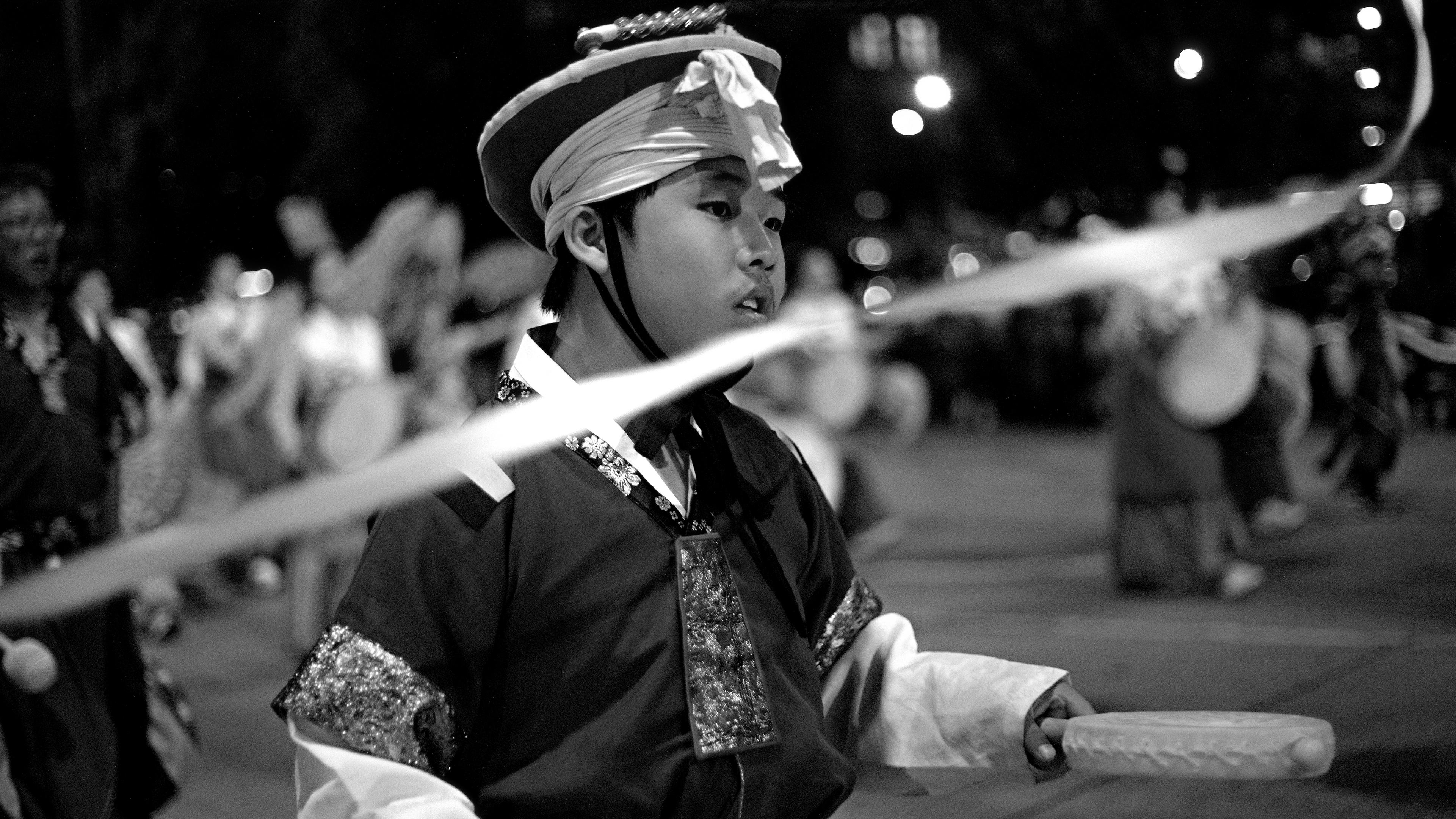 Monochrome photo of parade performer representing traditional Asian culture, clothing and instruments
