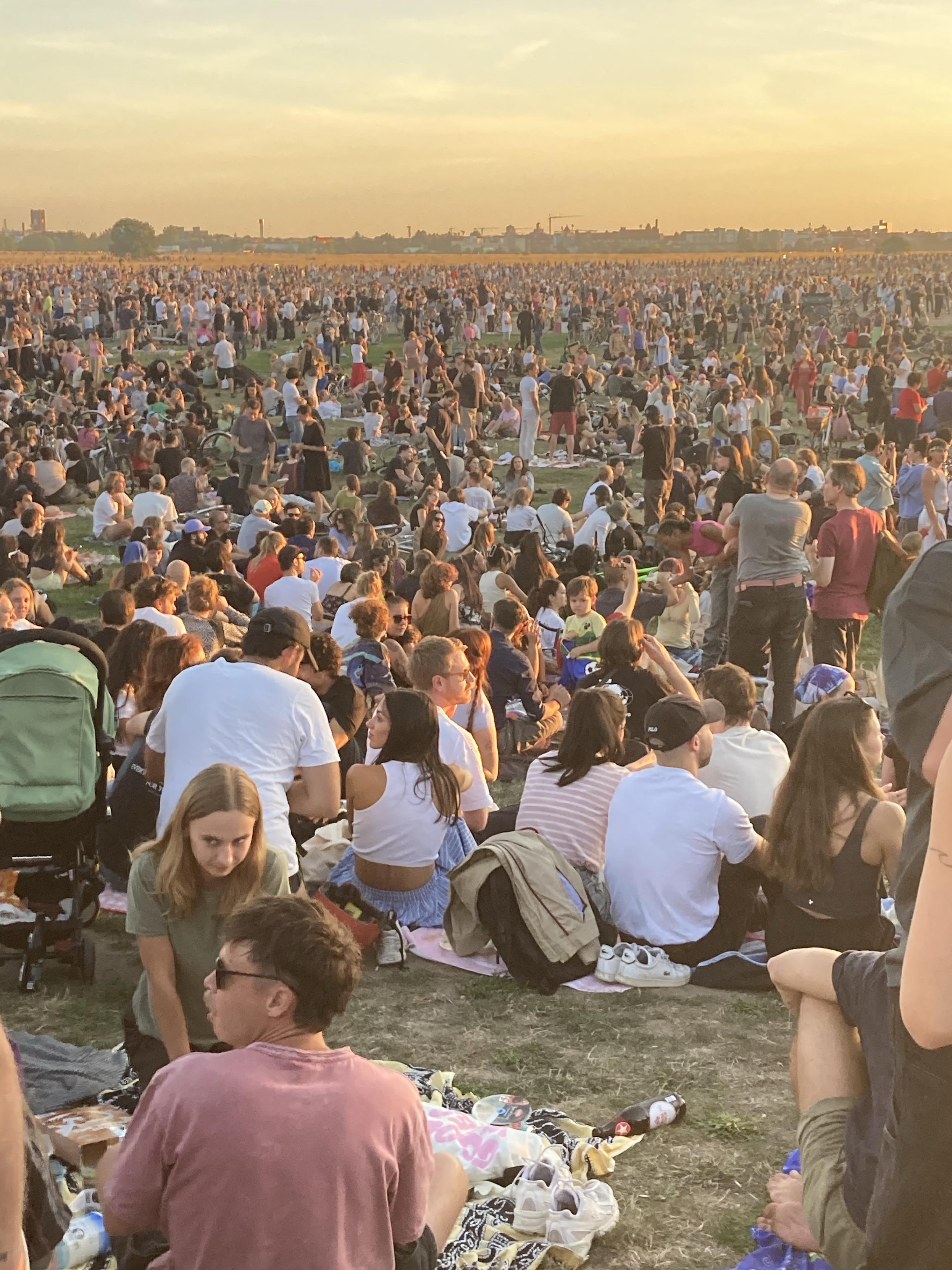 Thousands of people gather on the airport reaching into the distance with a haze filter (the moon)