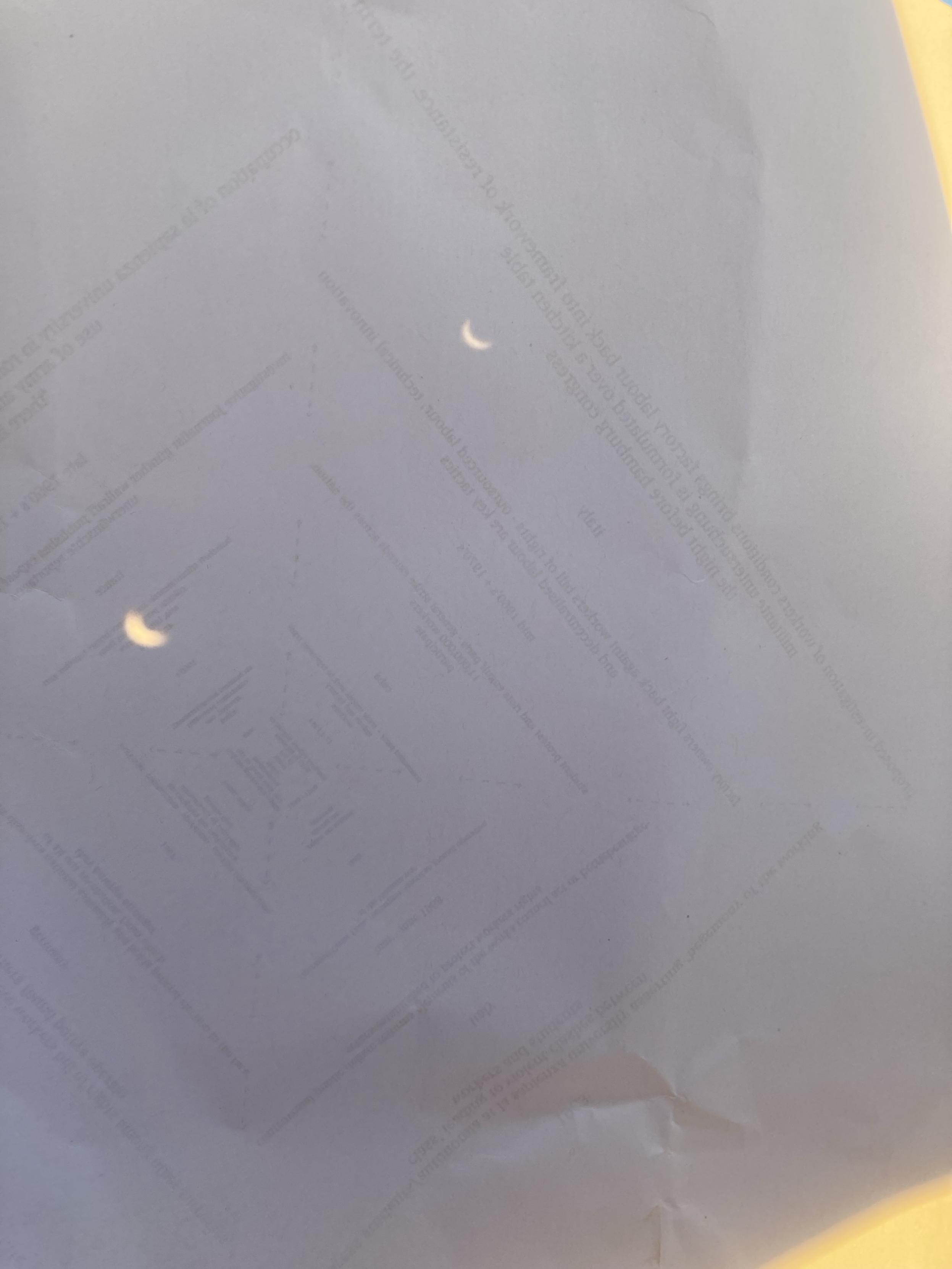The partial eclipse is revealed via the pinhole method onto a piece of paper in silloette.